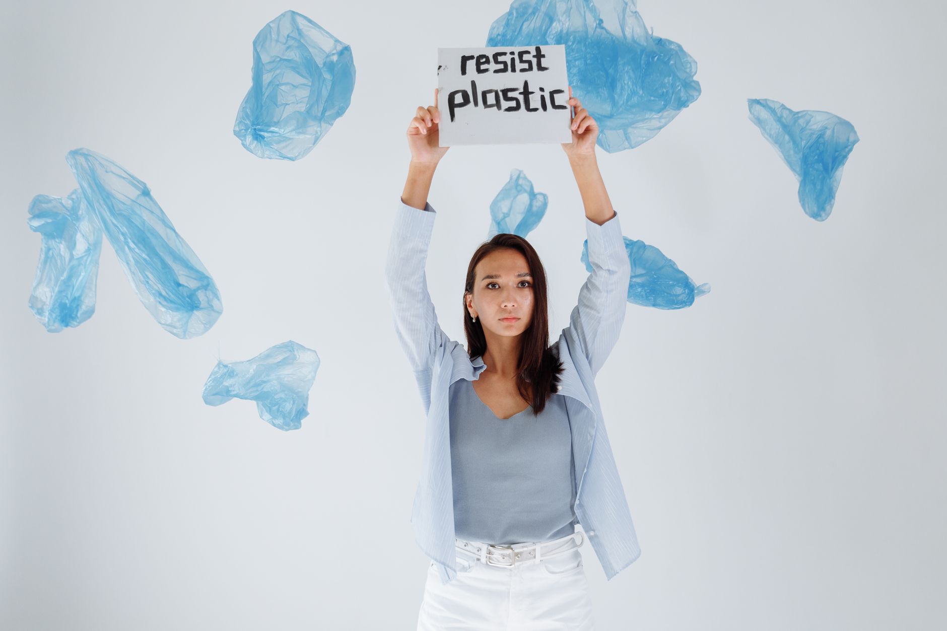 A determined woman holds a sign against plastic pollution amidst floating bags.