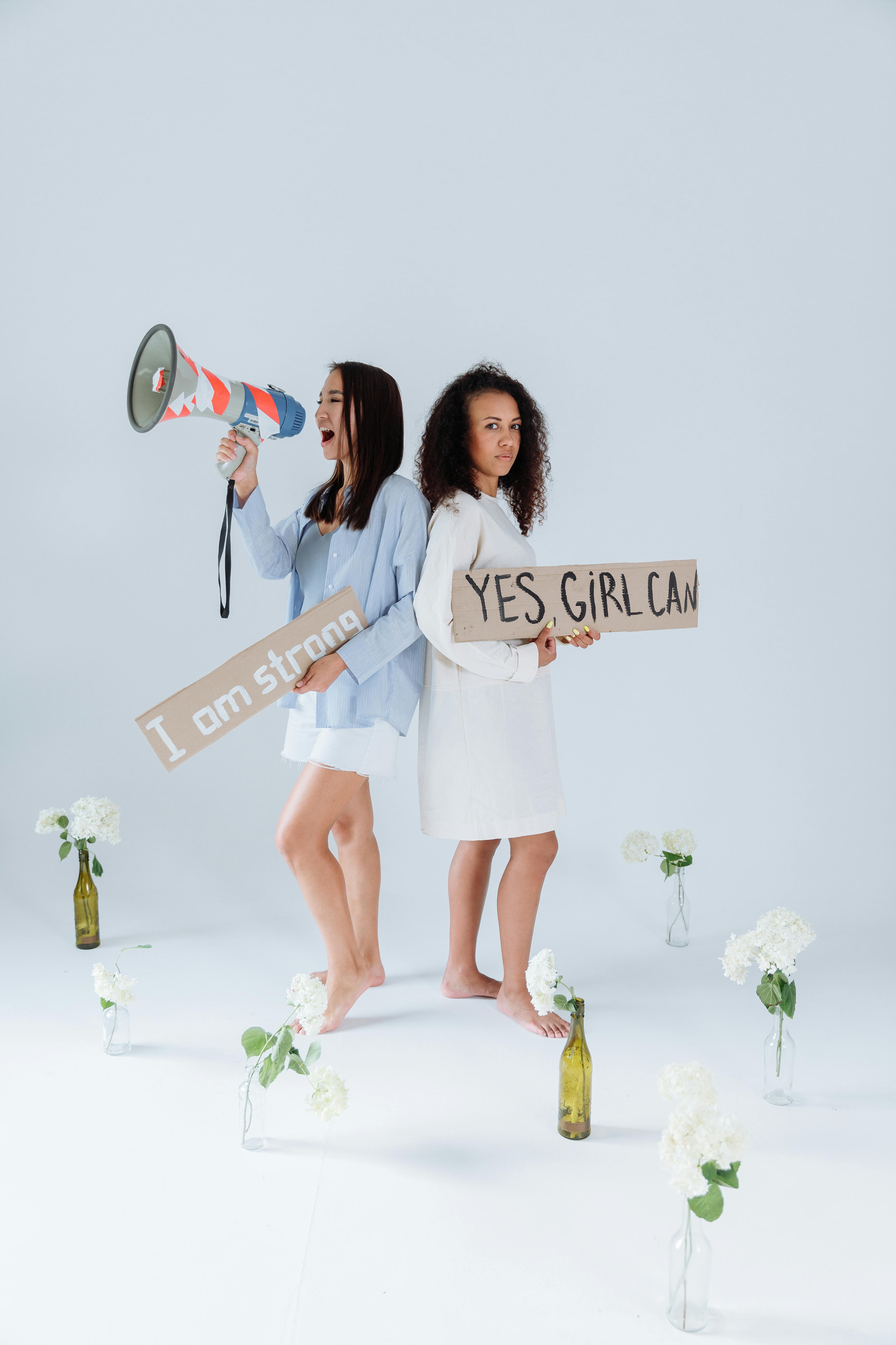 Two women with protest signs and flowers, symbolizing empowerment and activism.