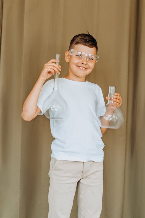 A Boy Wearing Safety Glasses while Holding Flasks