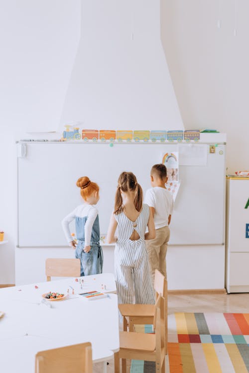 Three Kids Standing In Front of a Whiteboard and Studying