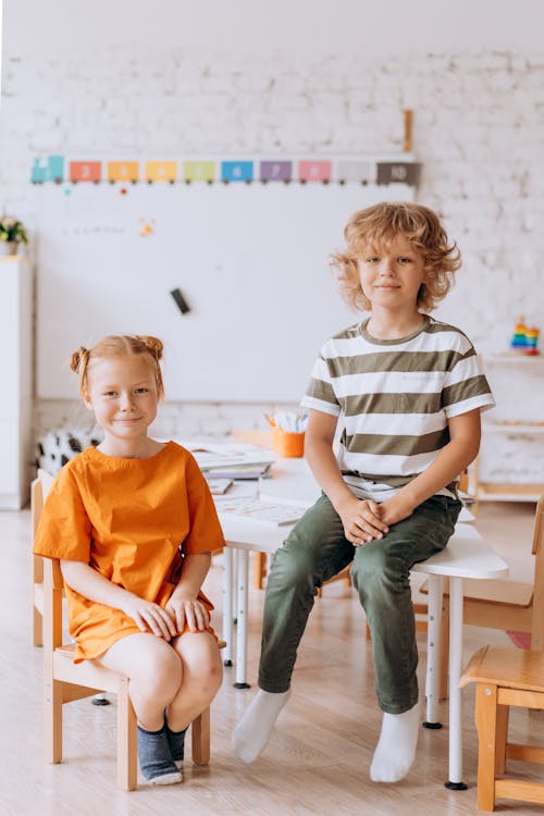Free Boy and a Girl Sitting On Wooden Chair and Table Stock Photo