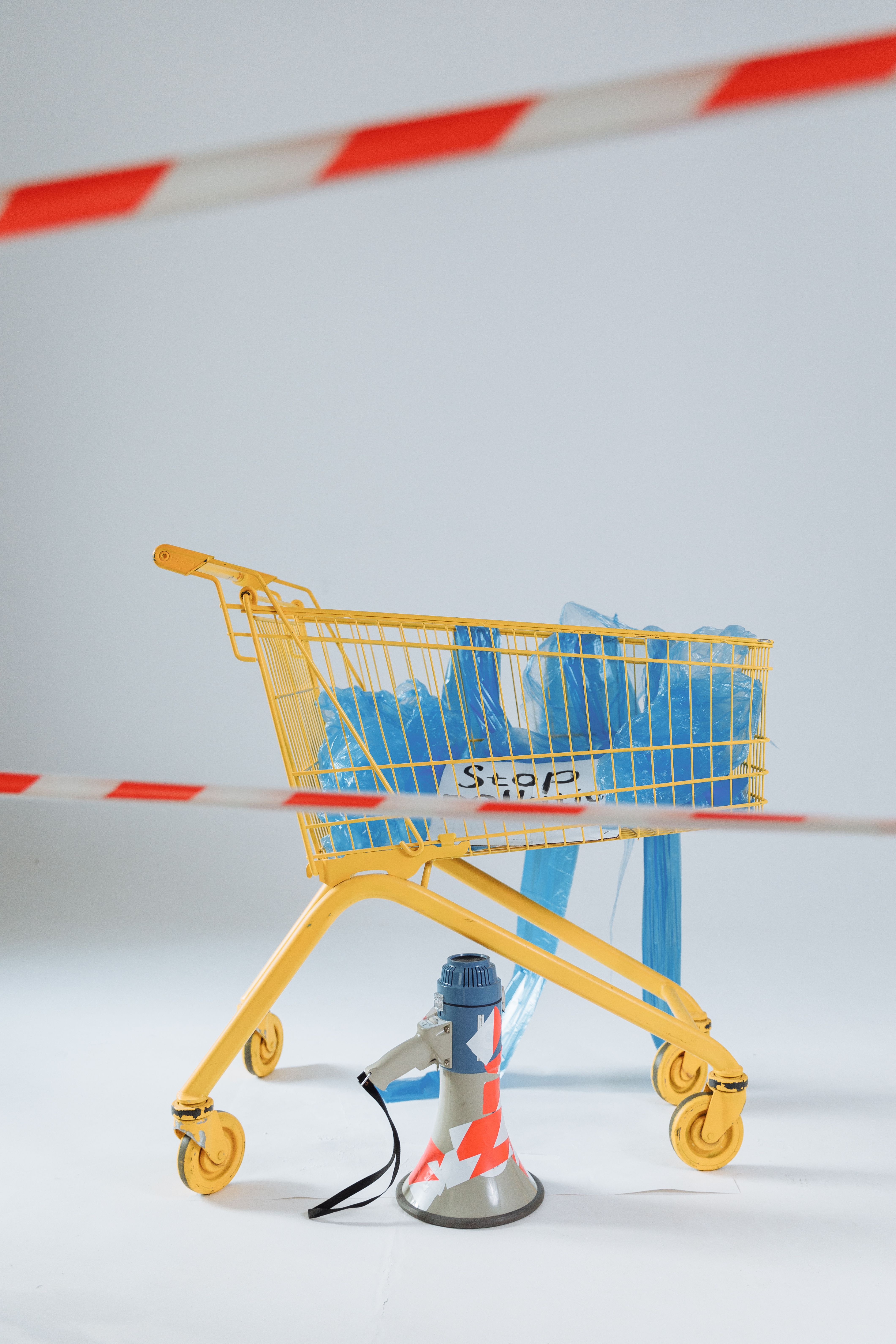 A shopping cart filled with plastic bags and a megaphone symbolizes activism against plastic pollution.