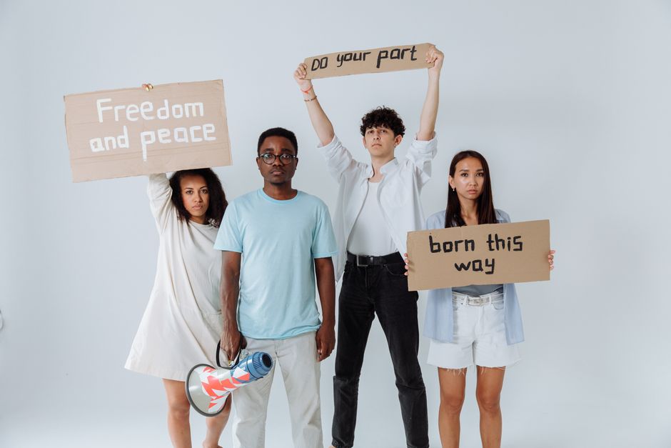 A group of diverse young adults holding protest signs promoting peace and unity.