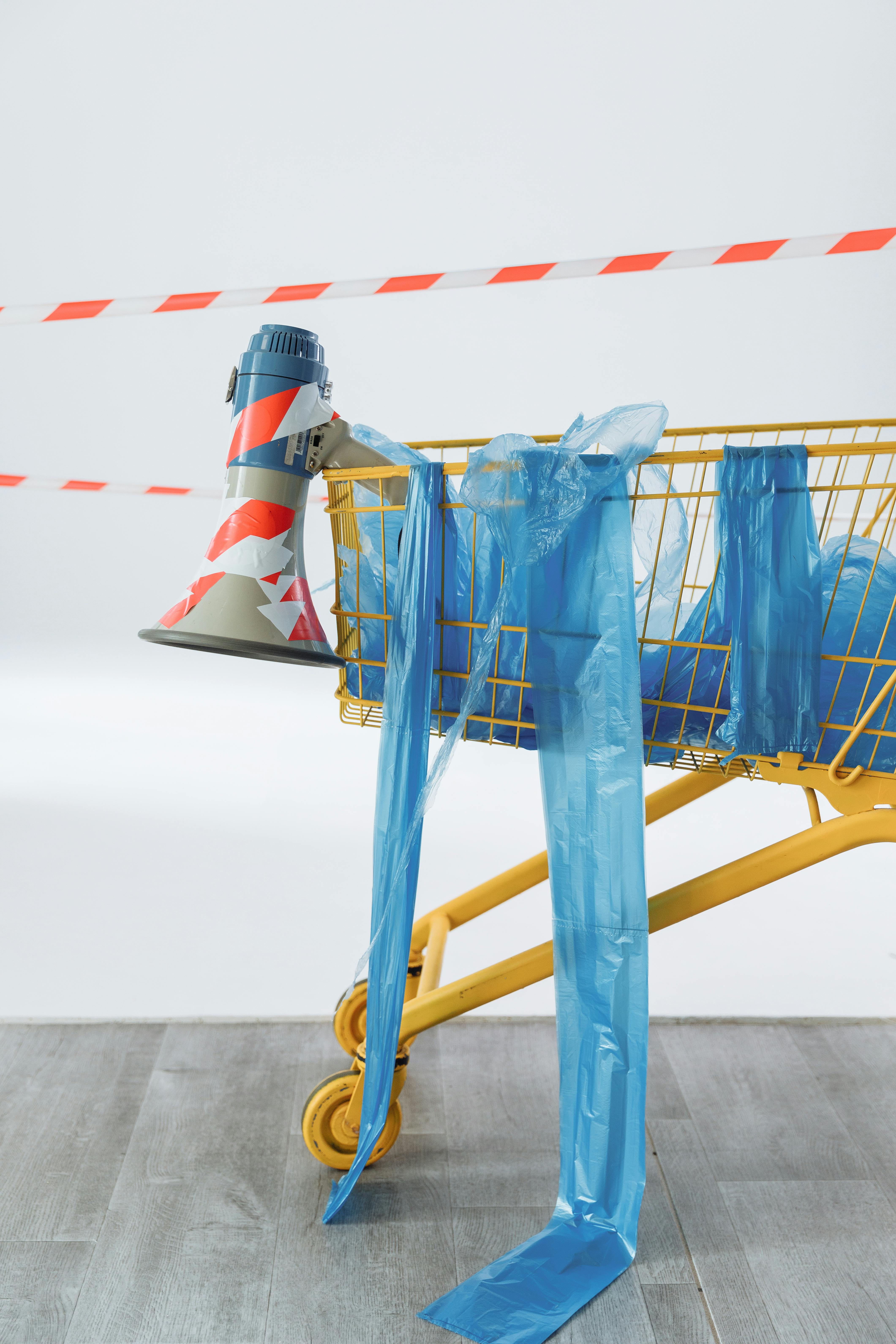 A shopping cart wrapped in plastic with a megaphone suggests themes of activism and communication.