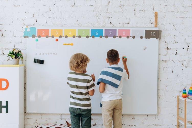 2 Boys Writing On The Whiteboard