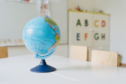 A vibrant globe sits on a table in a classroom, ideal for educational themes.