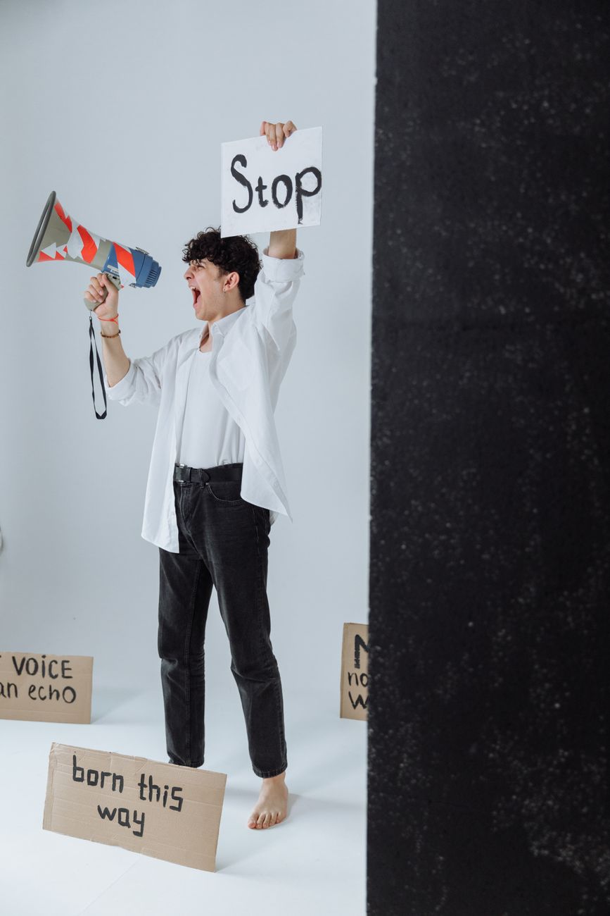 Um jovem protesta apaixonadamente, segurando um megafone e cartazes com mensagens contra a injustiça.