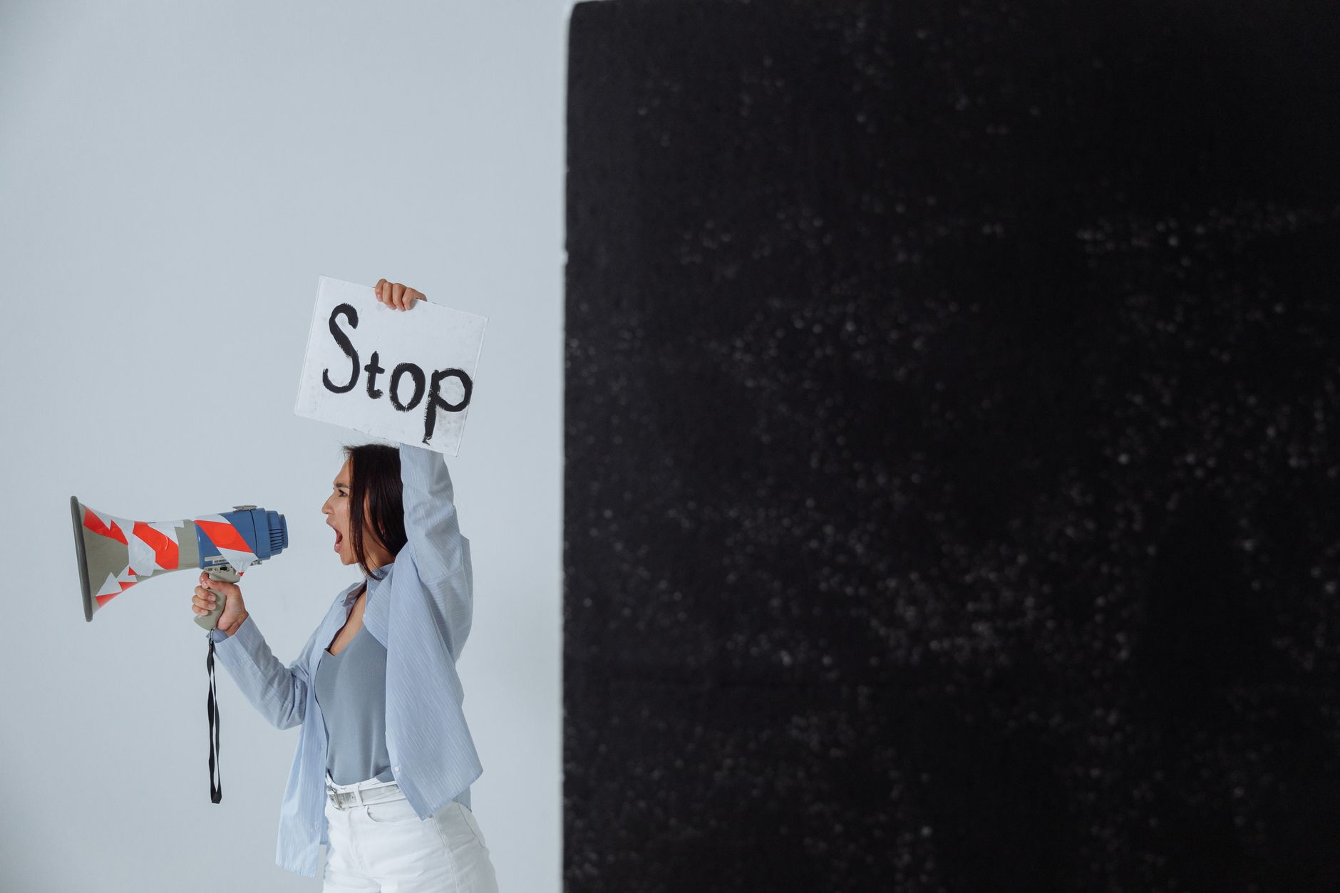 A woman holding a 'Stop' sign and megaphone in a protest, emphasis on activism and message conveyance.
