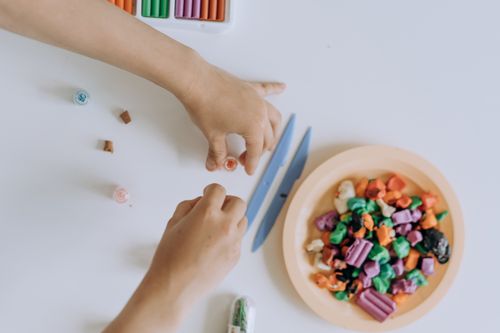 Free Hands crafting with colorful clay on a white surface, top view with artistic tools. Stock Photo