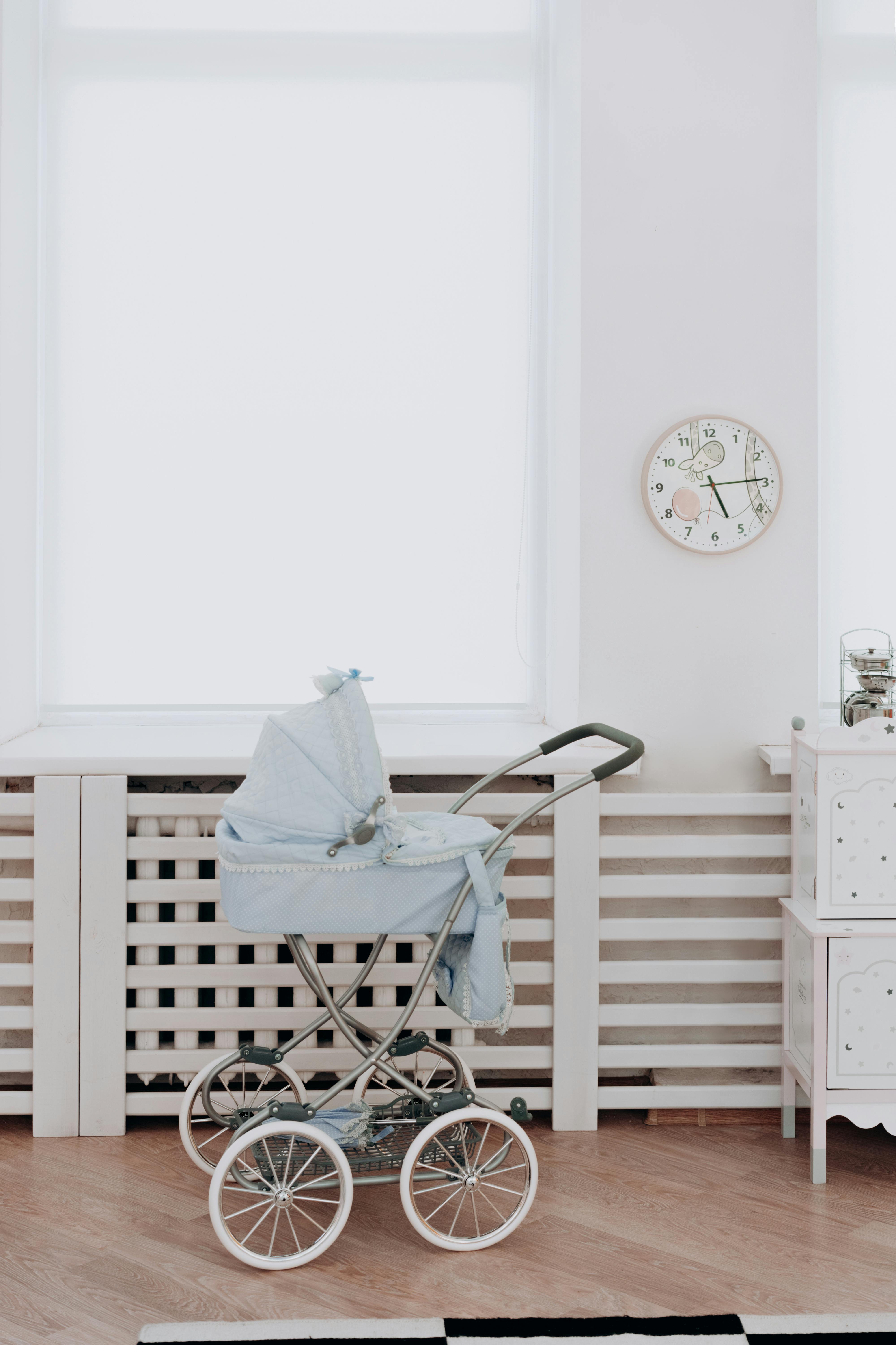 A blue vintage baby carriage in a bright, minimalist indoor setting.