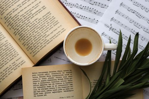 Free Top view of an empty coffee cup with books and sheet music creating a cozy and artistic atmosphere. Stock Photo