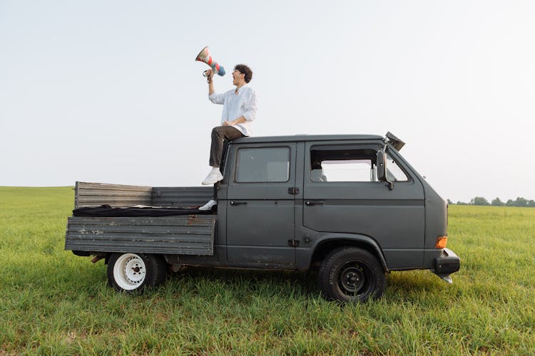 A Person Sitting At The Back Of The Van Shouting Through Megaphone