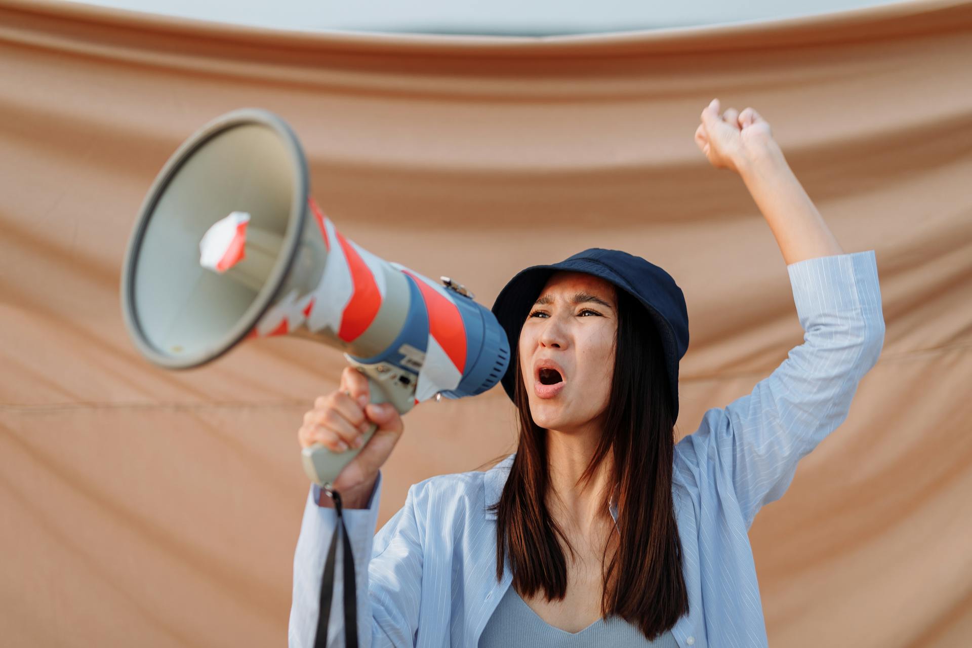 A Woman Screaming on a Megaphone Protesting with a Clenched Fist