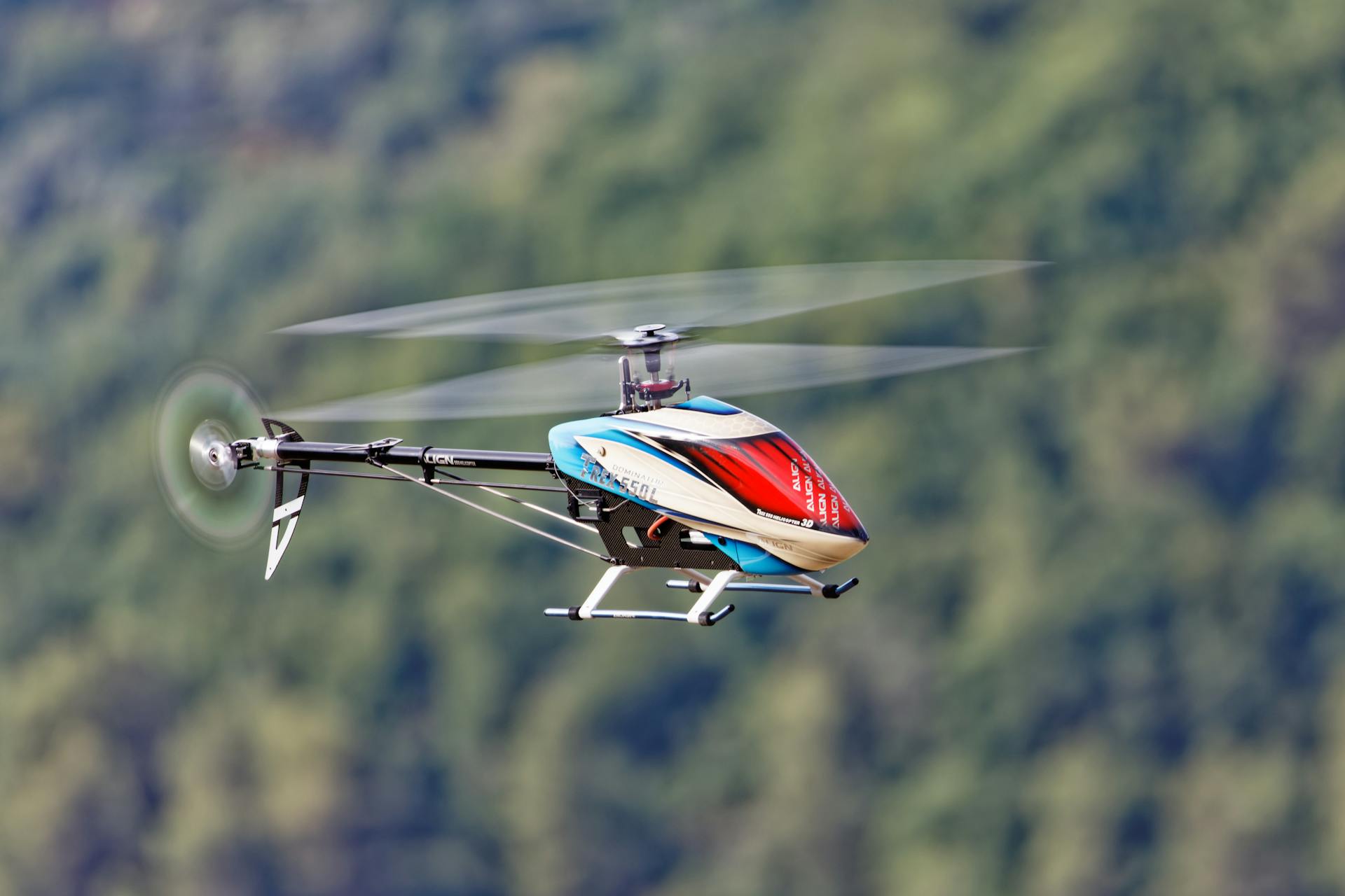 Close-up of a remote-controlled helicopter flying against a blurred natural background.