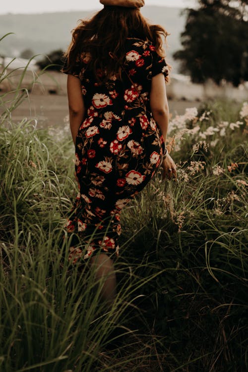 A Woman in Black Floral Dress Walking on the Grass
