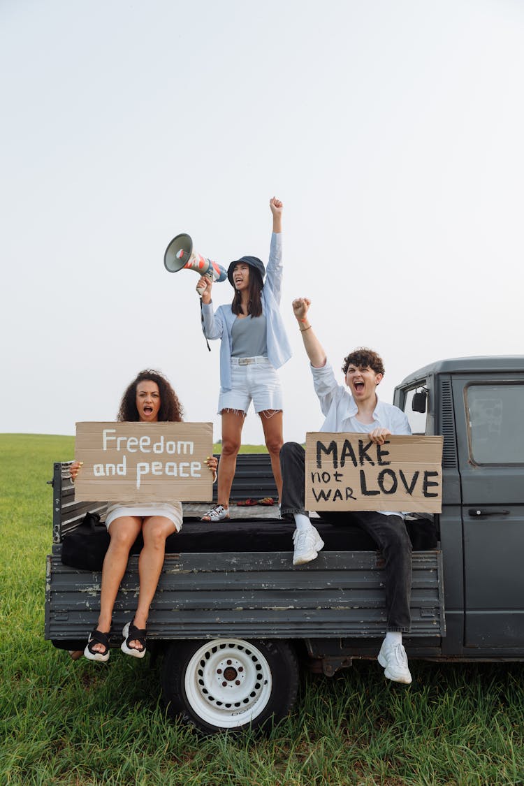 People Sitting At The Back Of The Van Holding Signages