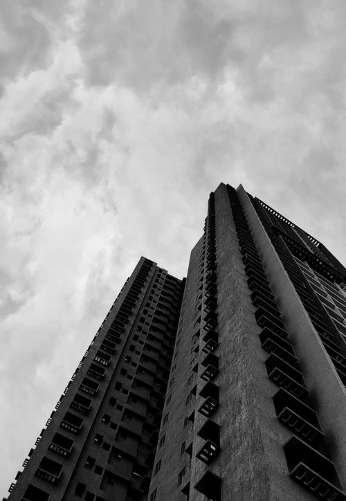 Free A striking black and white photo of tall high-rise buildings under a cloudy sky. Stock Photo