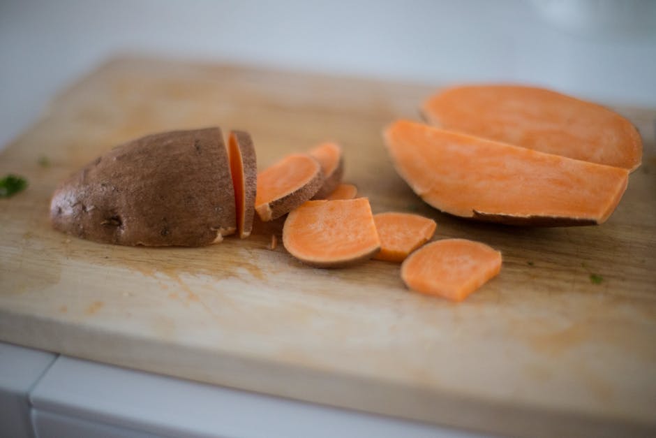 unpeeled and halved sweet potato on a cutting board.