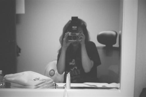 Grayscale Photo of Person Taking Photo of Herself In Front Of A Mirror