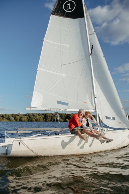 A Kid and Elderly Man Sitting on a Sailboat