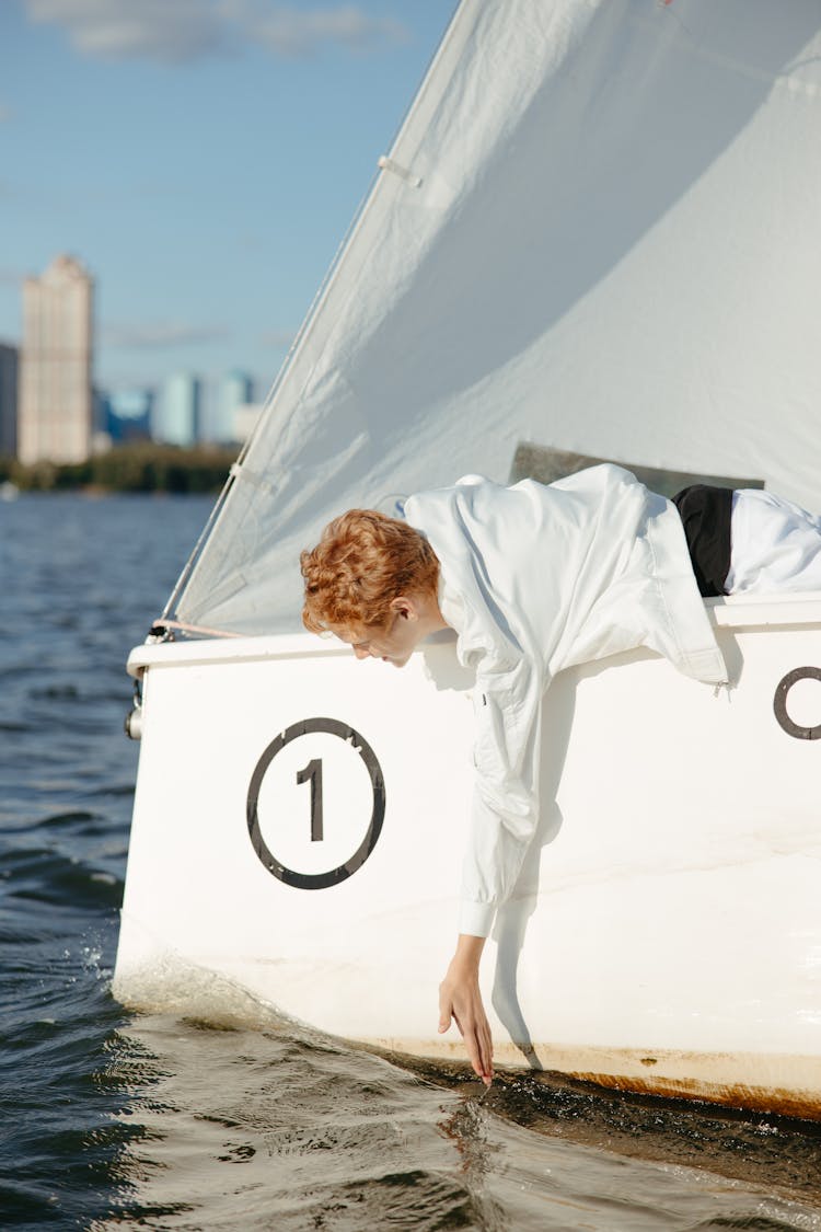 Redhead Man Leaning From Sailboat Splashing Water