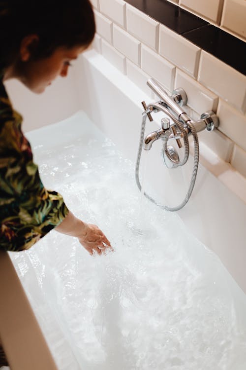 Close-Up Shot of a Woman Touching a Water in a Bathtub