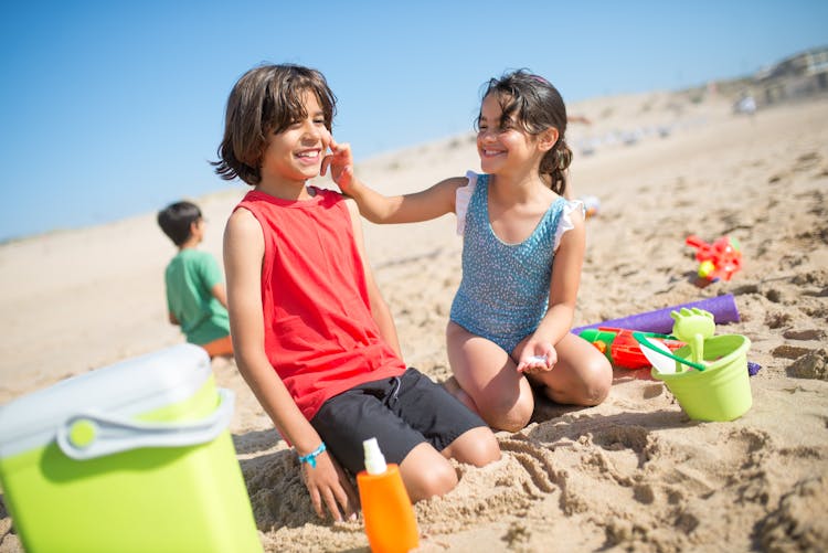 Young Girl Putting Sunscreen On A Boy