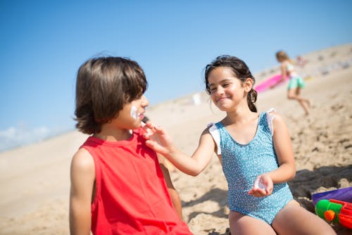 Free A Girl and a Boy Sitting on Beach Sand Having Fun  Stock Photo
