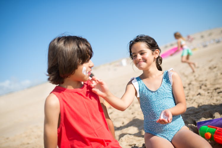 A Girl And A Boy Sitting On Beach Sand Having Fun 