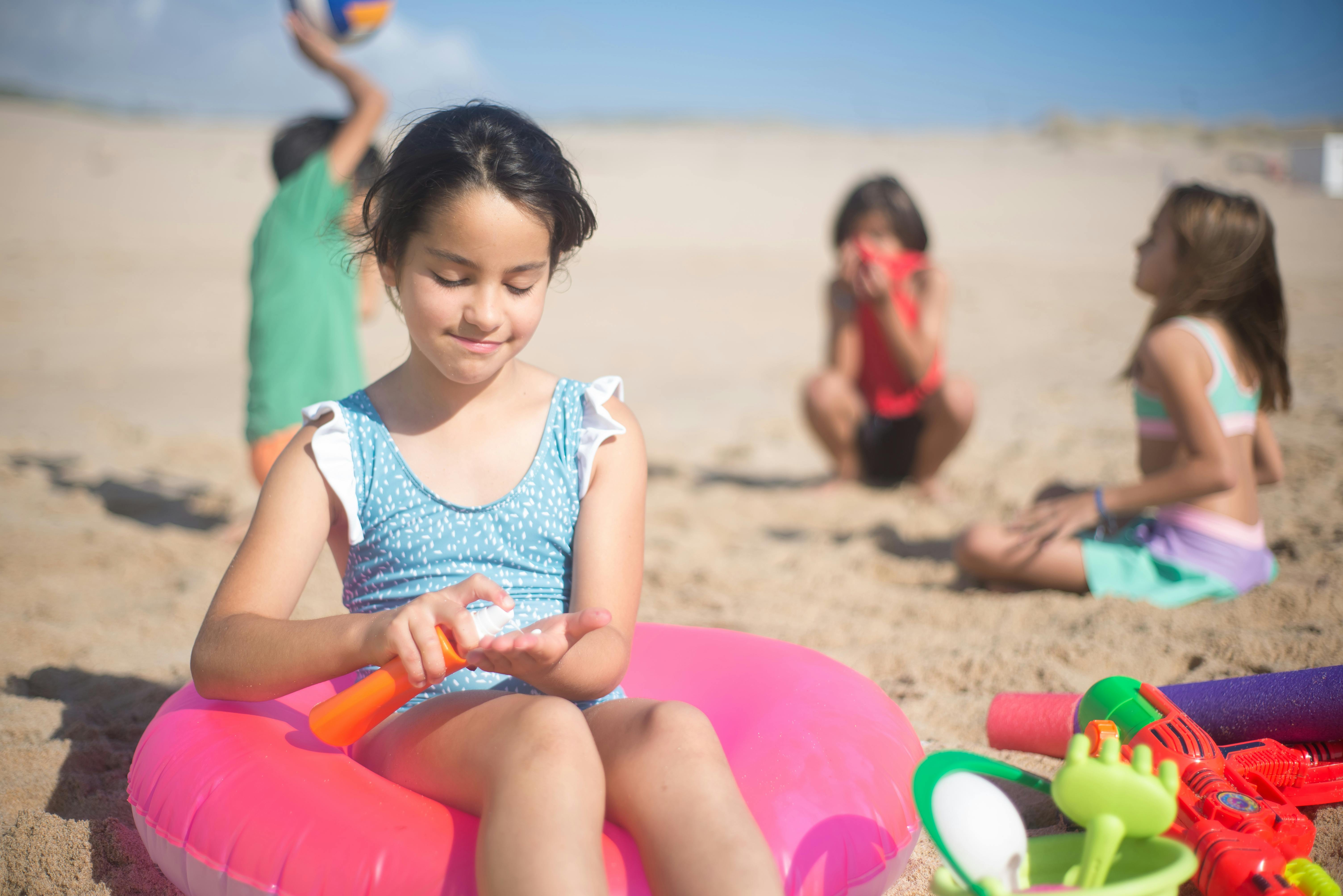 Children playing on a sunny beach, applying sunscreen, and enjoying summer activities.