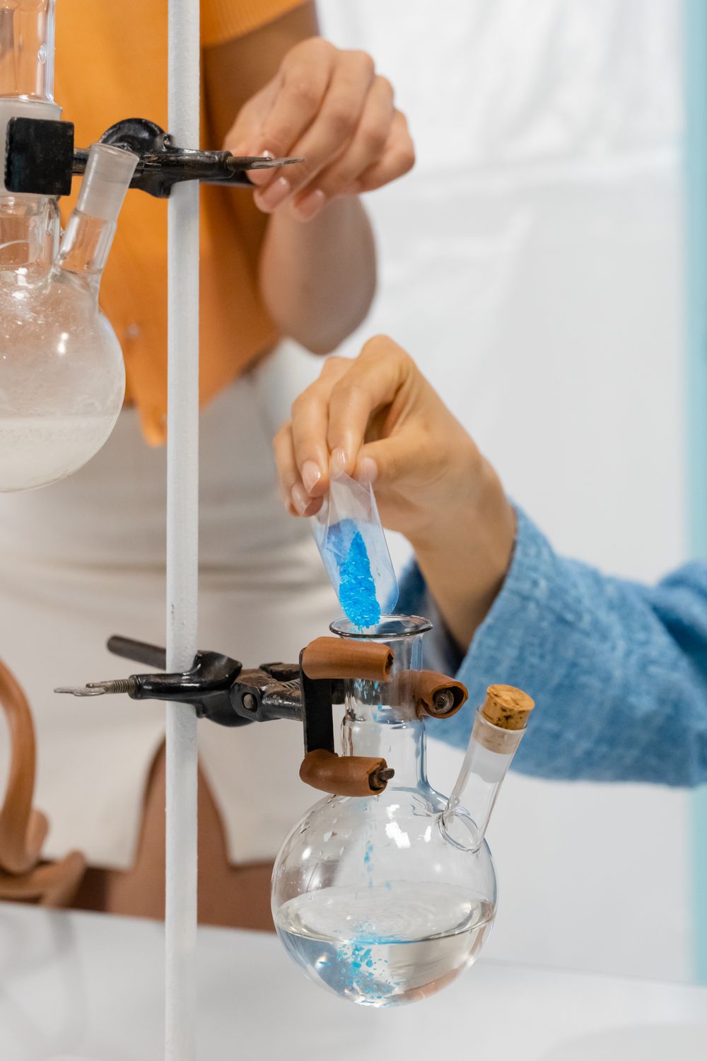 Person Pouring Powder Into a Glass Apparatus · Free Stock Photo