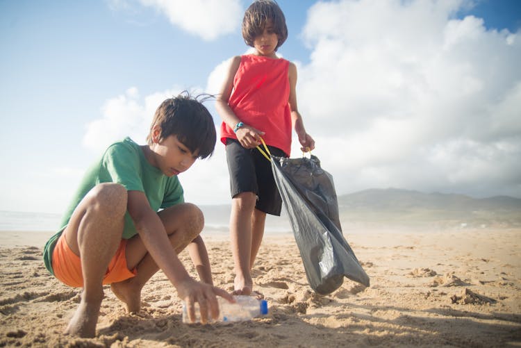 A Boy Picking Up A Plastic Water Bottle