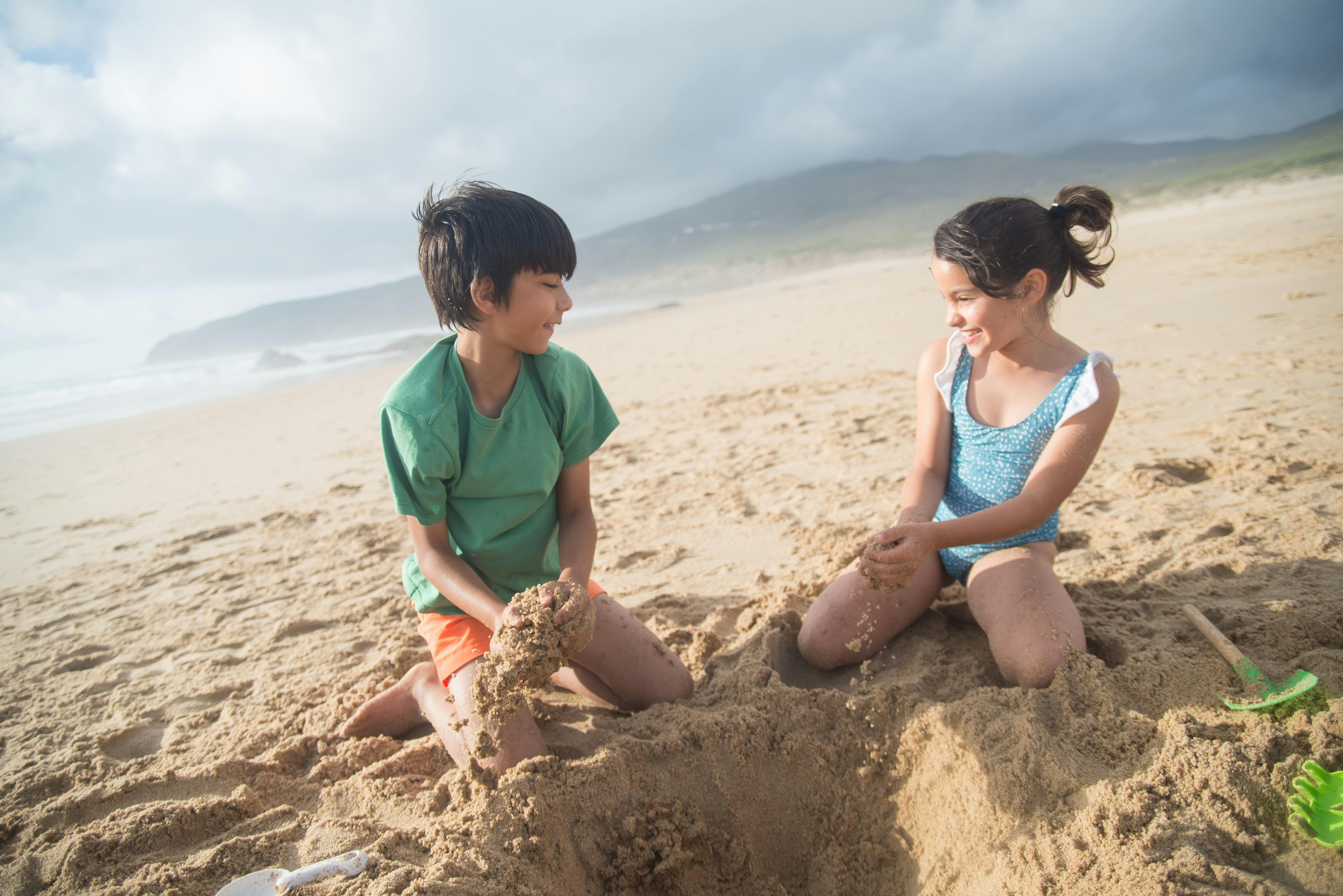 a boy and a girl playing the brown sand