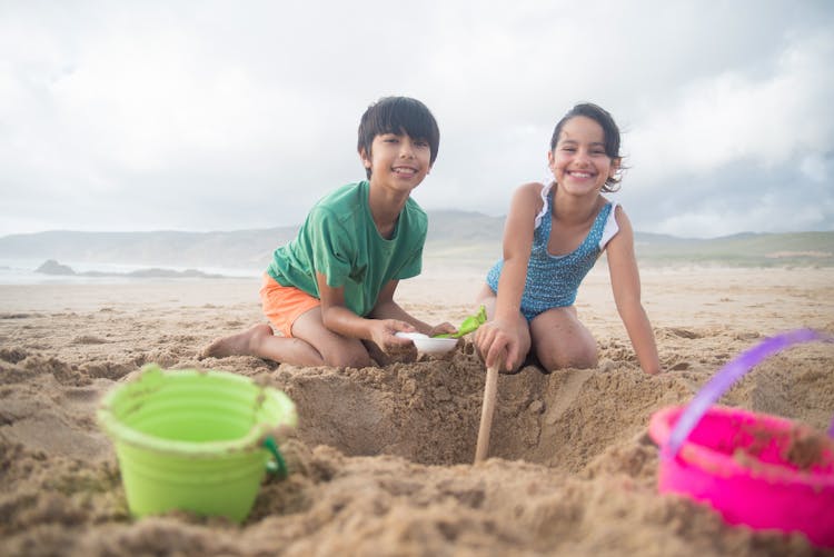 Kids Creating A Hole On The Brown Sand