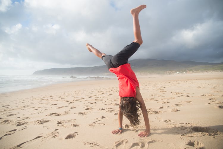 A Person Doing Handstand At The Beach