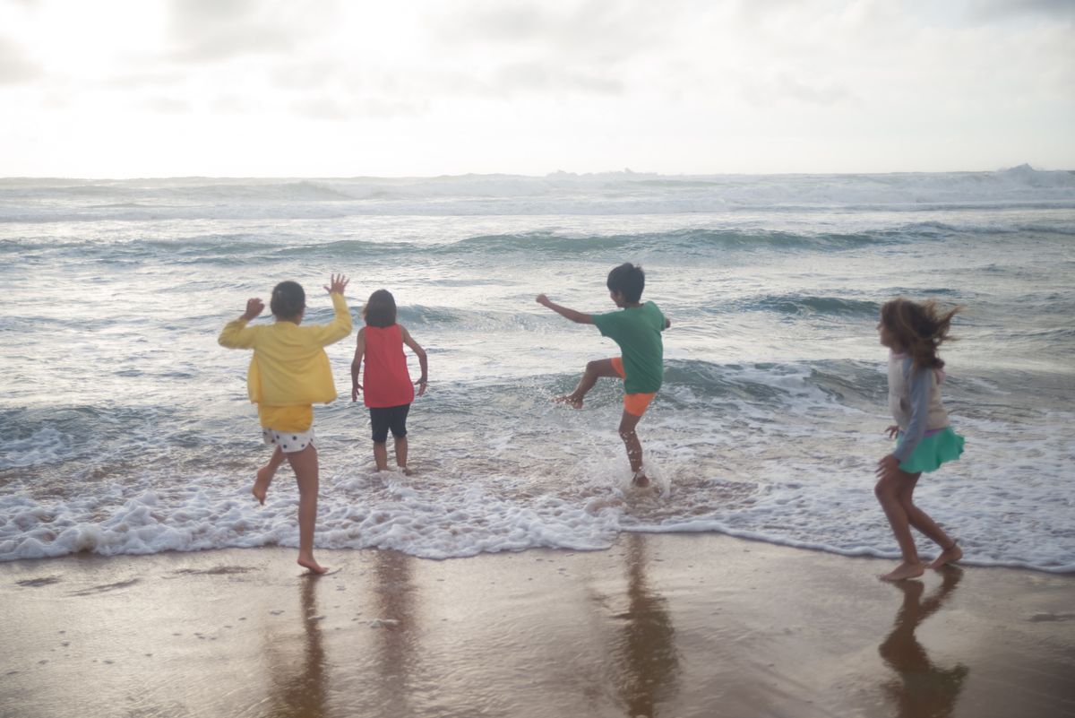 Children playing joyfully by the ocean shore, capturing the essence of summer fun.