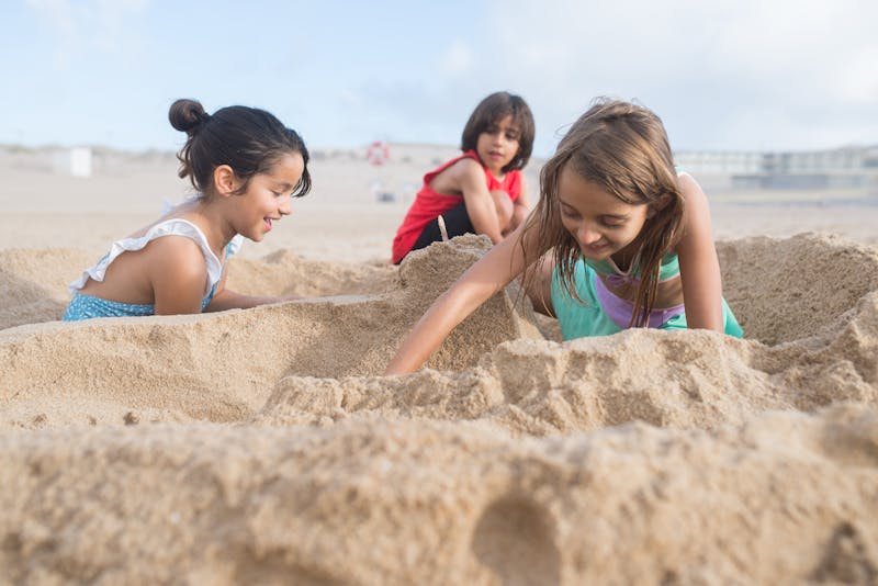 Children happily playing in the sand at a sunny European beach with blue sky