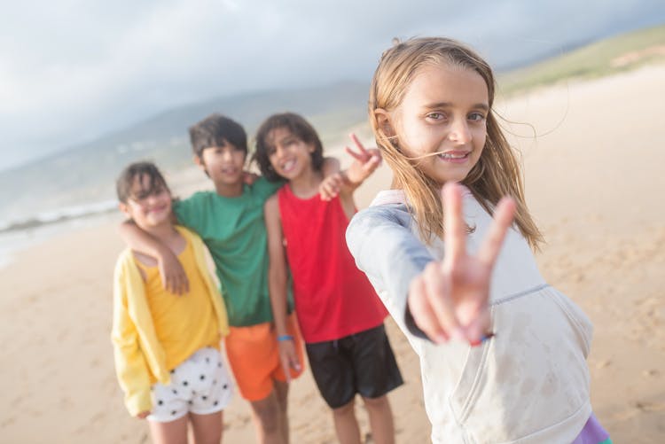 A Girl Doing Peace Sign With The Kids At Her Back