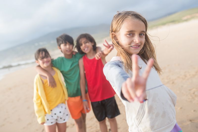Group of kids having fun on a beach, smiling and making peace signs