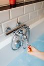 A Person Checking the Temperature of the Water from a Faucet