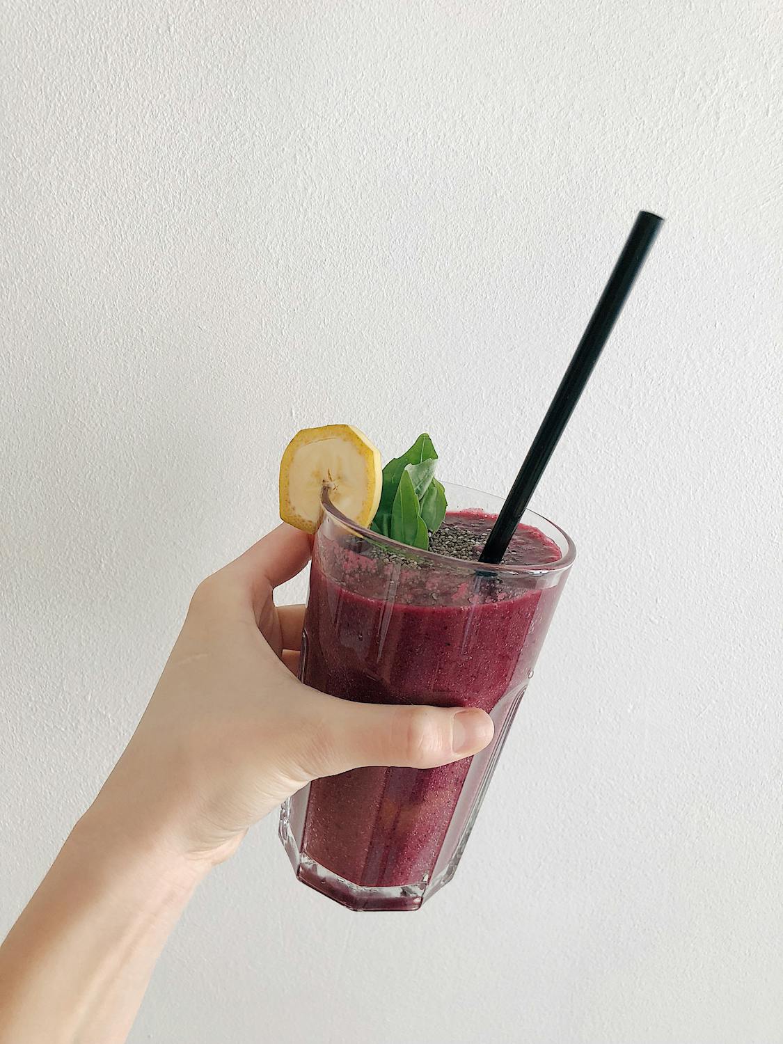 colorful dark purple smoothie packed with fruits and topped with a banana slice and mint