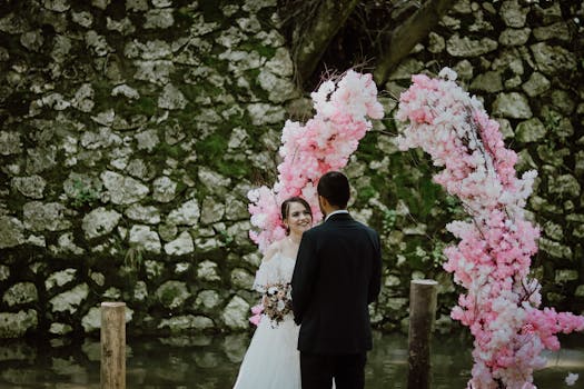 A couple at a romantic outdoor wedding ceremony with a vibrant floral arch.