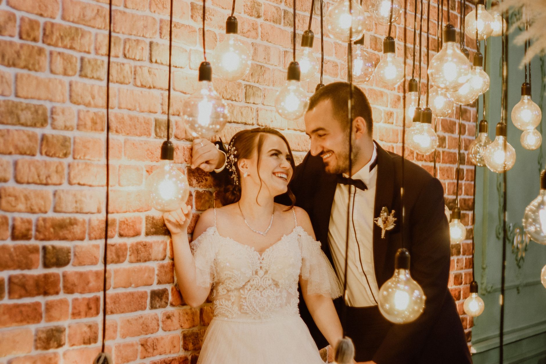 A loving wedding couple sharing a joyful moment under ambient lights.