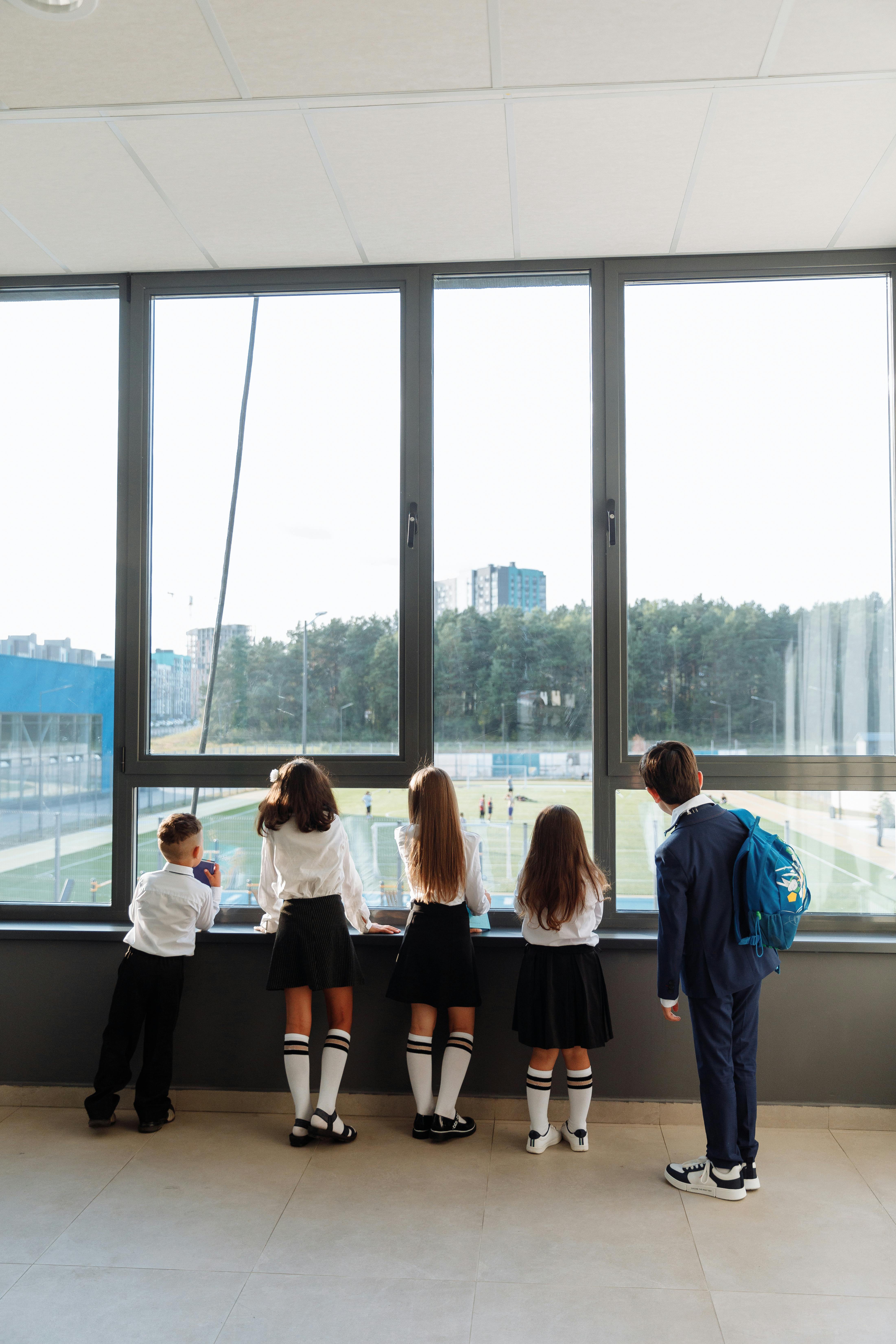 back view of students in school uniform looking outside