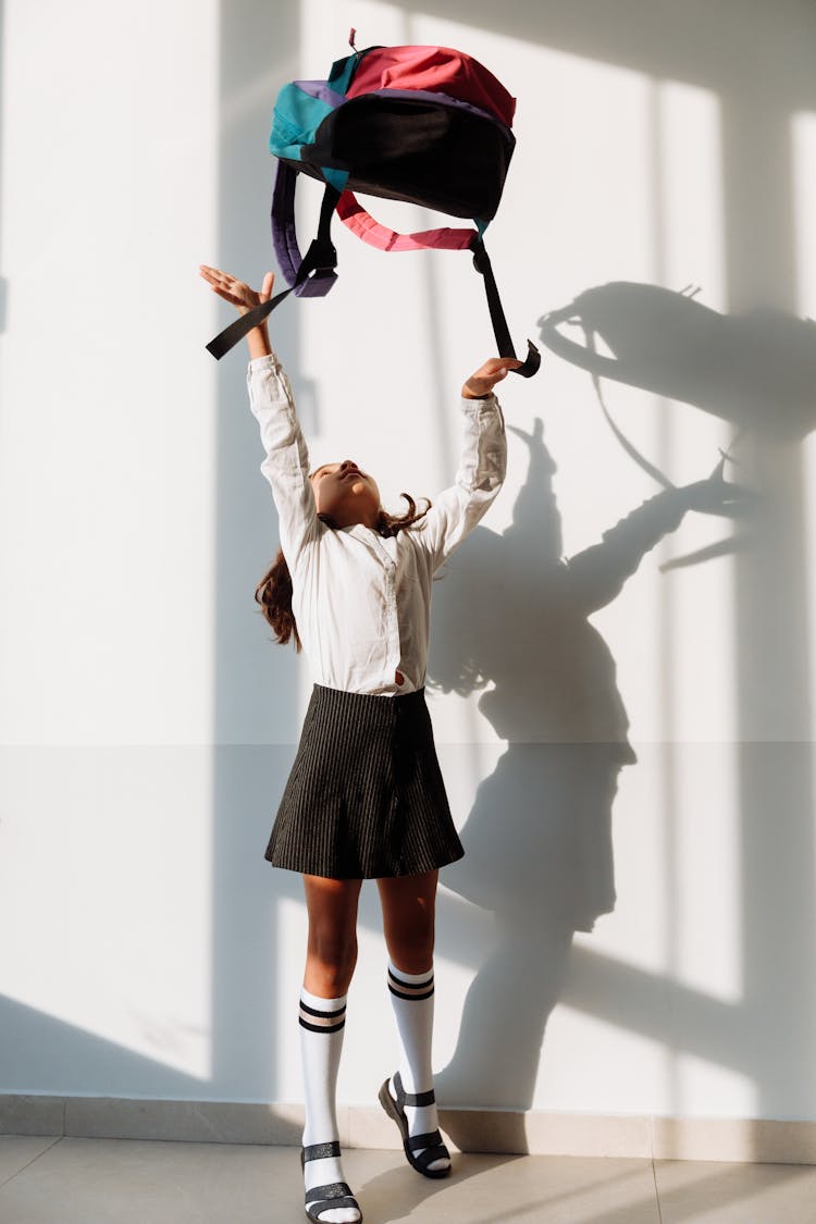 Girl In School Uniform Throwing Her Backpack