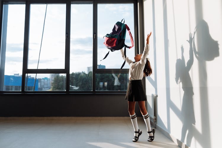 Girl In School Uniform Throwing Her Backpack