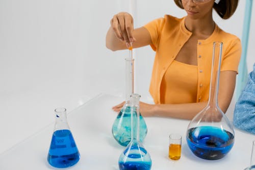A Woman Holding a Test Tube Over a Flat Bottom Flask 