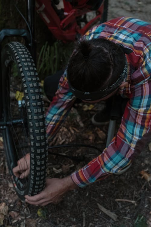 Free Photo of a Man Fixing the Wheel of a Bicycle Stock Photo