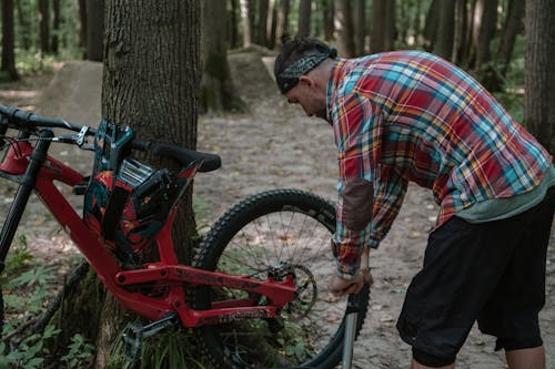 Man Wearing Plaid Shirt Fixing a Mountain Bike