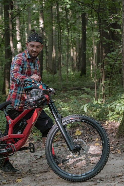 A Man Walking with a Mountain Bike in a Forest